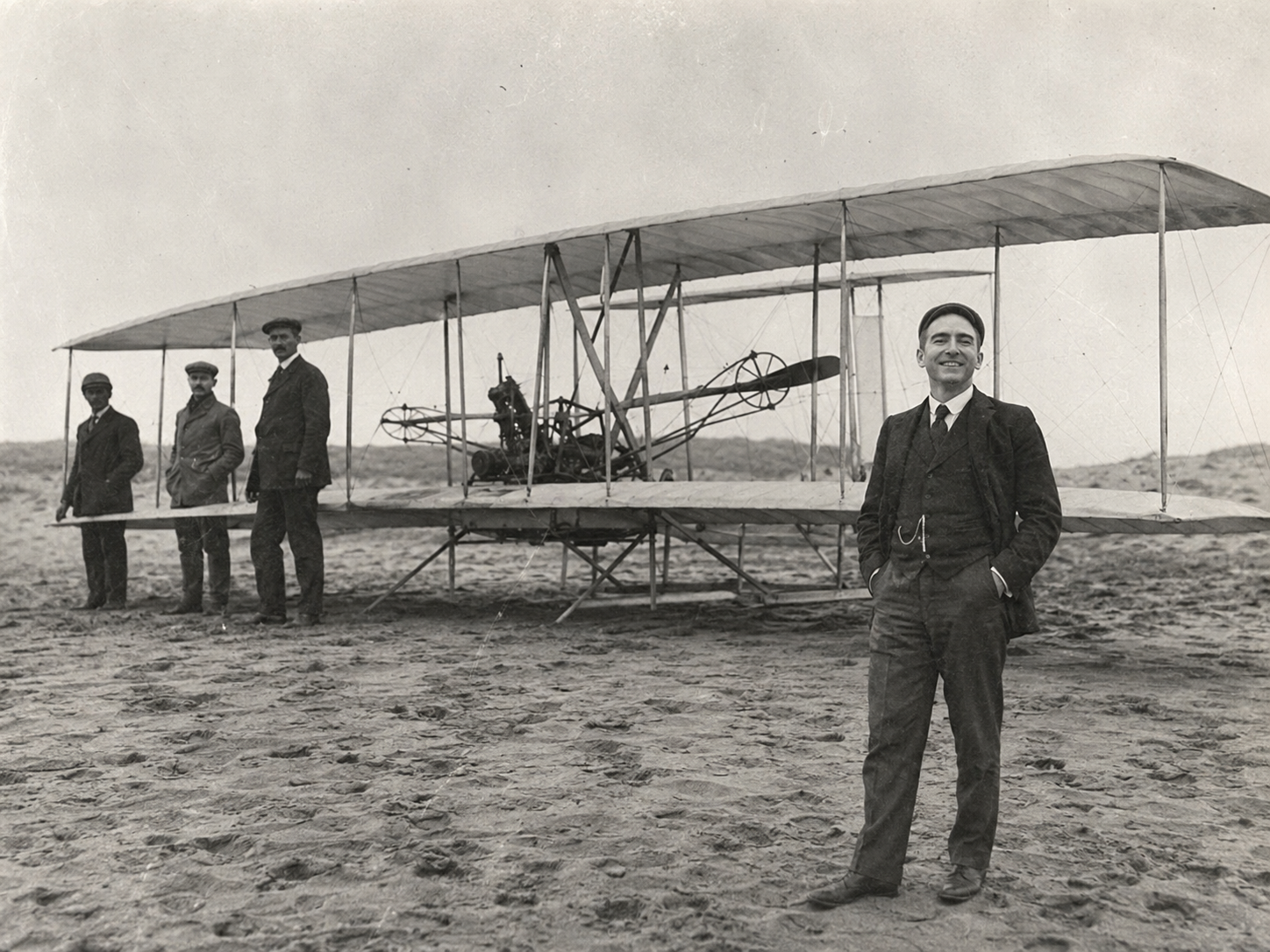 Archival photograph of Matthew Black standing before the 1903 Flyer at Kitty Hawk
